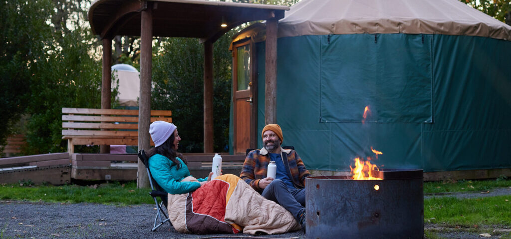 Retreat to Reconnect itinerary cover photo showing a couple enjoying a camp fire in the campground at Champoeg State Heritage Area near Wilsonville, Oregon