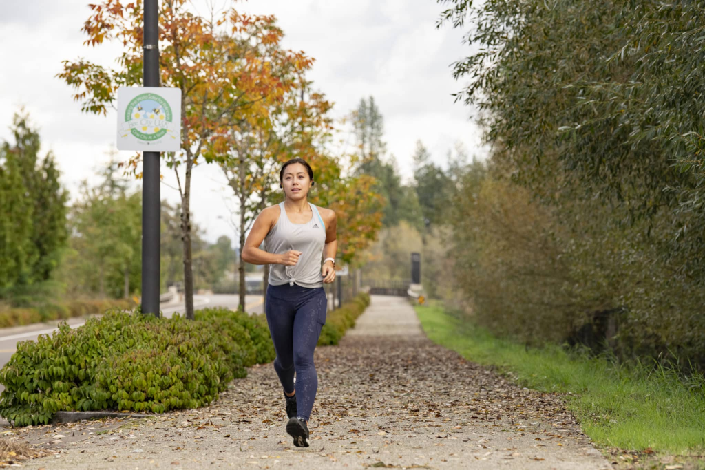 Woman running along a trail at the Coffee Lake Wetlands
