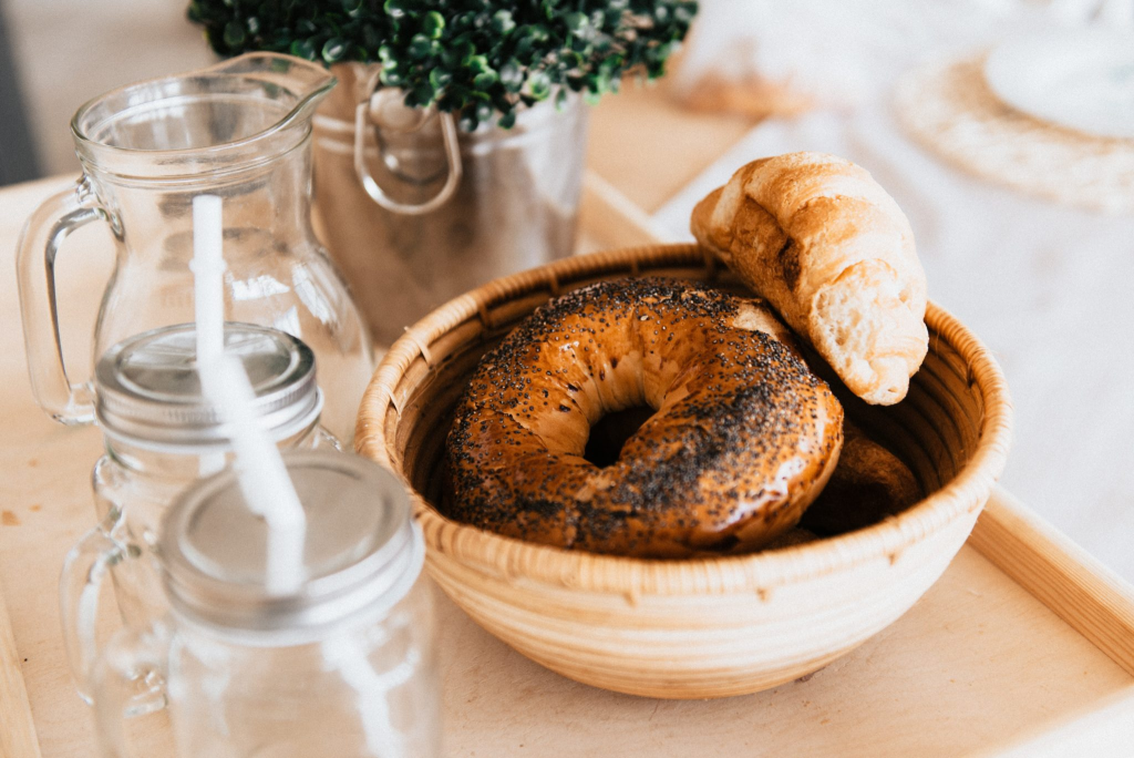 Bagels in a wooden basket next to glass mason jars