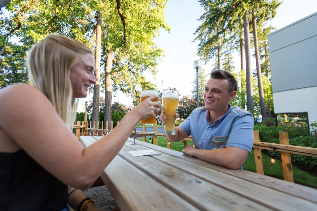 A couple on a bench toasting beer 