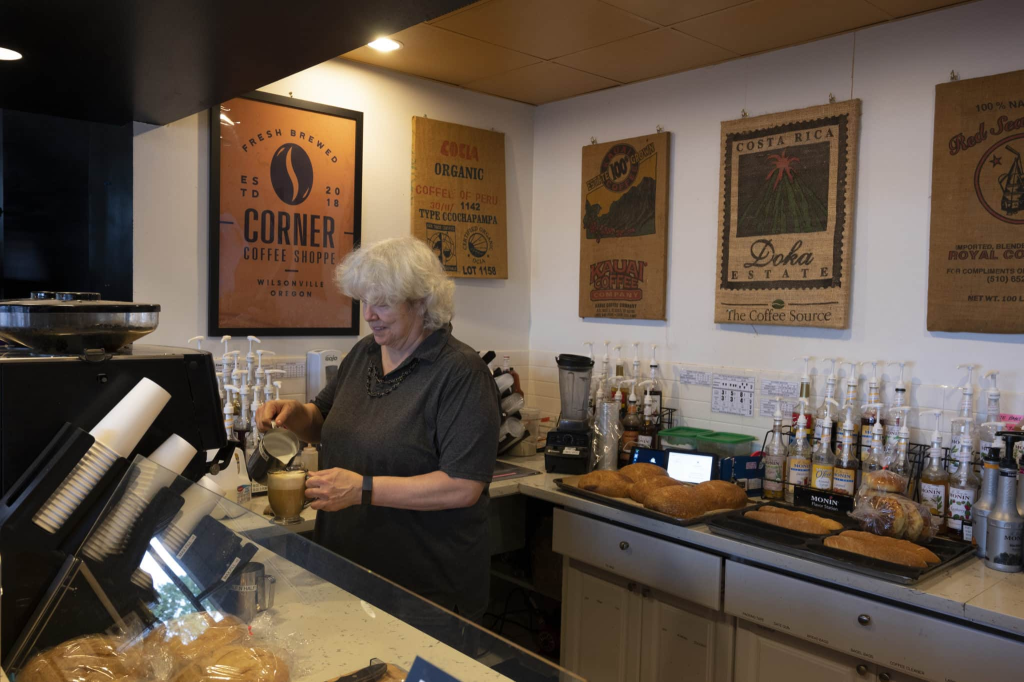 Older woman pouring foam milk over coffee