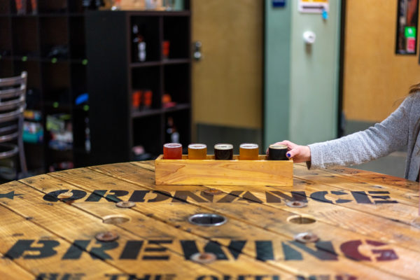 Woman grabbing a glass of beer from a beer flight