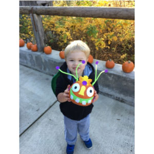 Boy holding up a decorated pumpkin