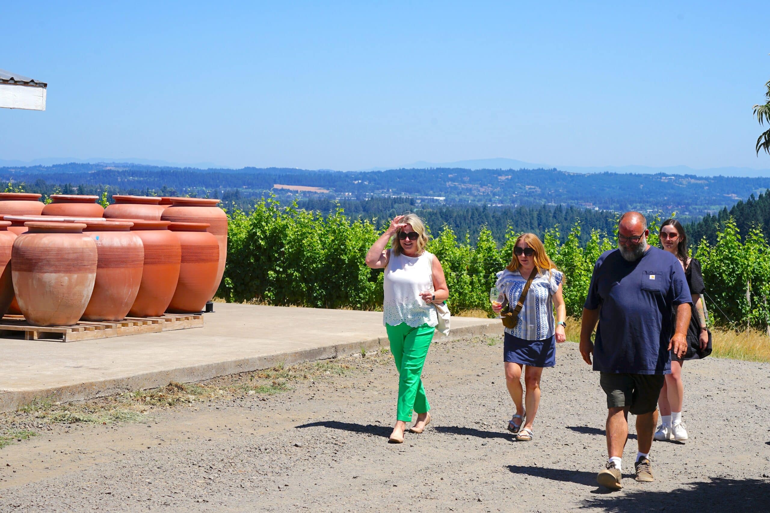 Photo of happy customers walking with the owner of Beckham Estates Vineyard at the vineyard with terracotta wine amphoras and Wilsonville, Oregon in the background