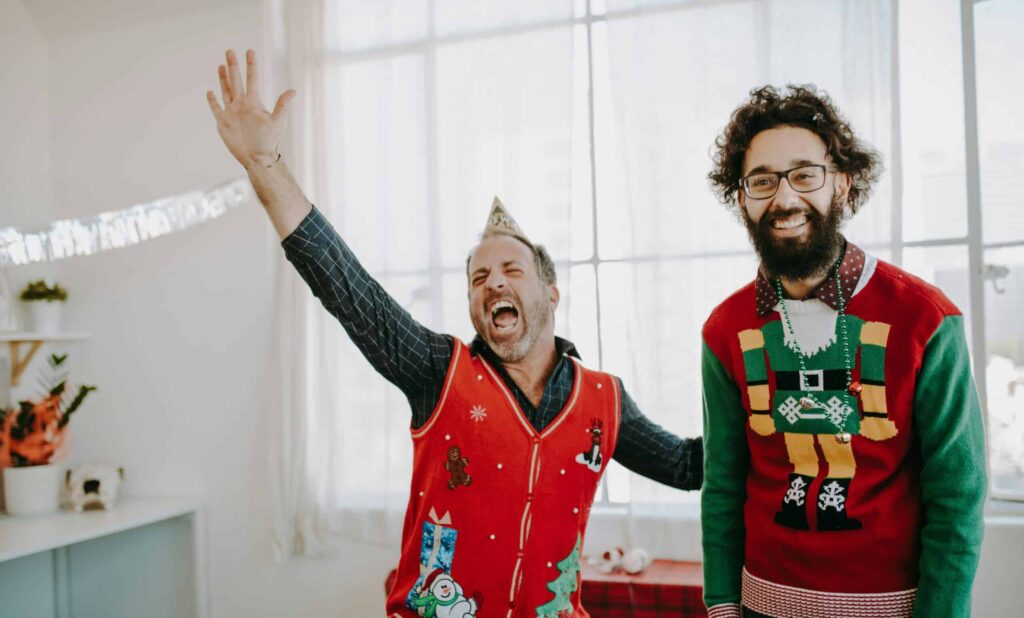 photo of two people celebrating while wearing ugly Christmas sweaters