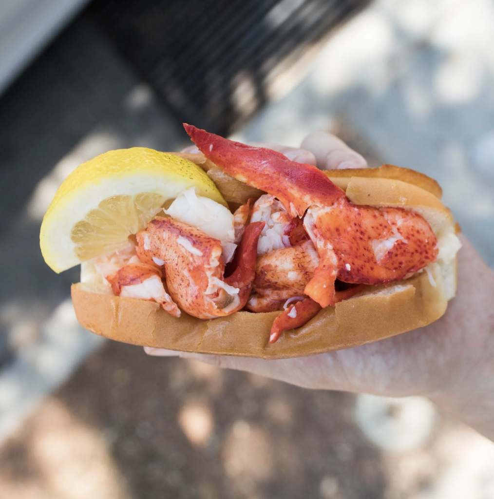 Photo of someone holding a lobster roll from Cousins Maine Lobster in Wilsonville, Oregon at Vanguard Brewing