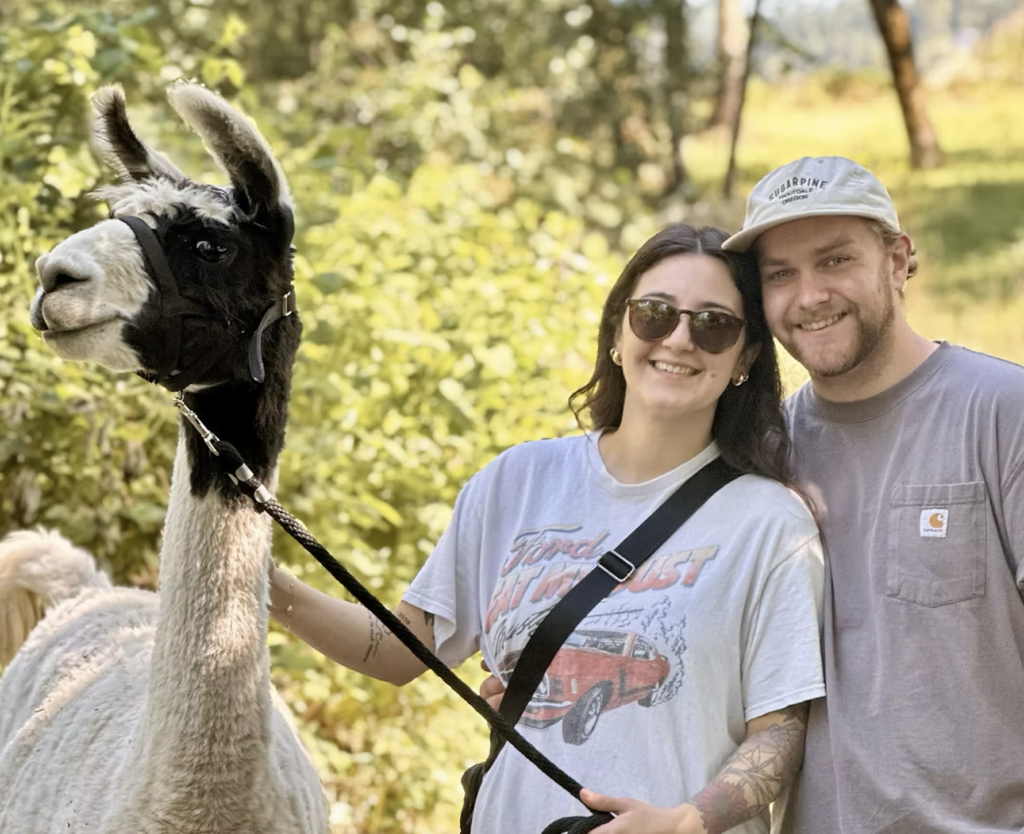 photo of a couple taking a picture with a llama at Frog Pond Farm