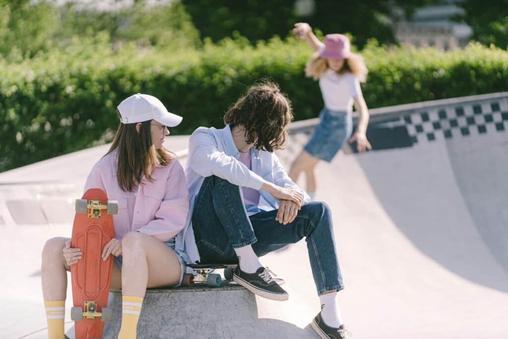 photo of young adults hanging out and skateboarding at a skate park