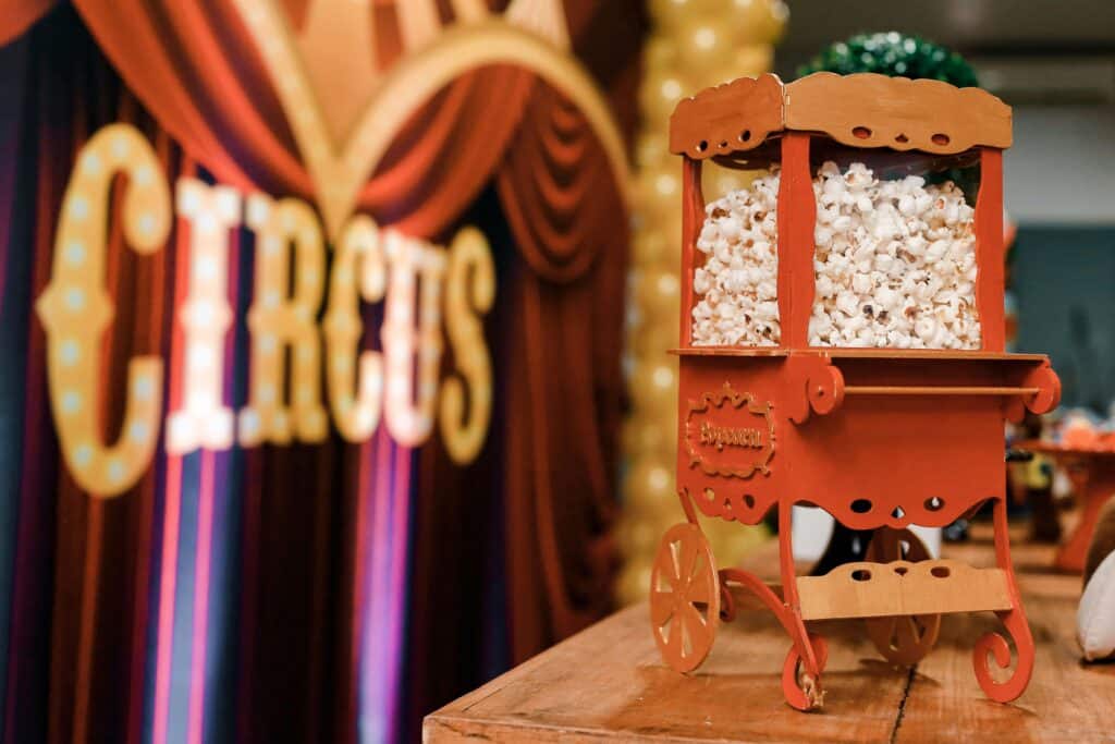 photo inside a circus tent of a sign that says "circus" next to a mini vintage popcorn cart